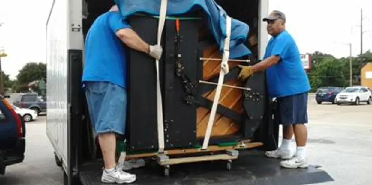 Professional piano movers carefully transporting a piano